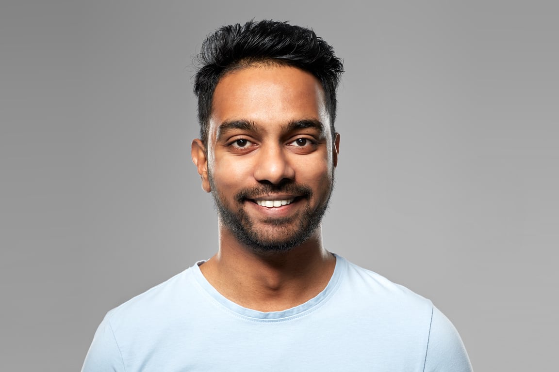 Smiling Young Indian Man over Grey Background